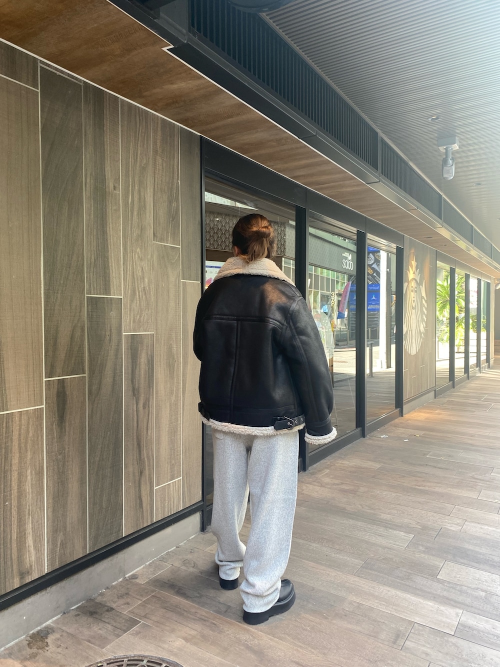 ブラック系のムートンコート、グレー系のその他パンツ、ブラック系のブーツを着用したレディースの秋コーディネートの2枚目の写真