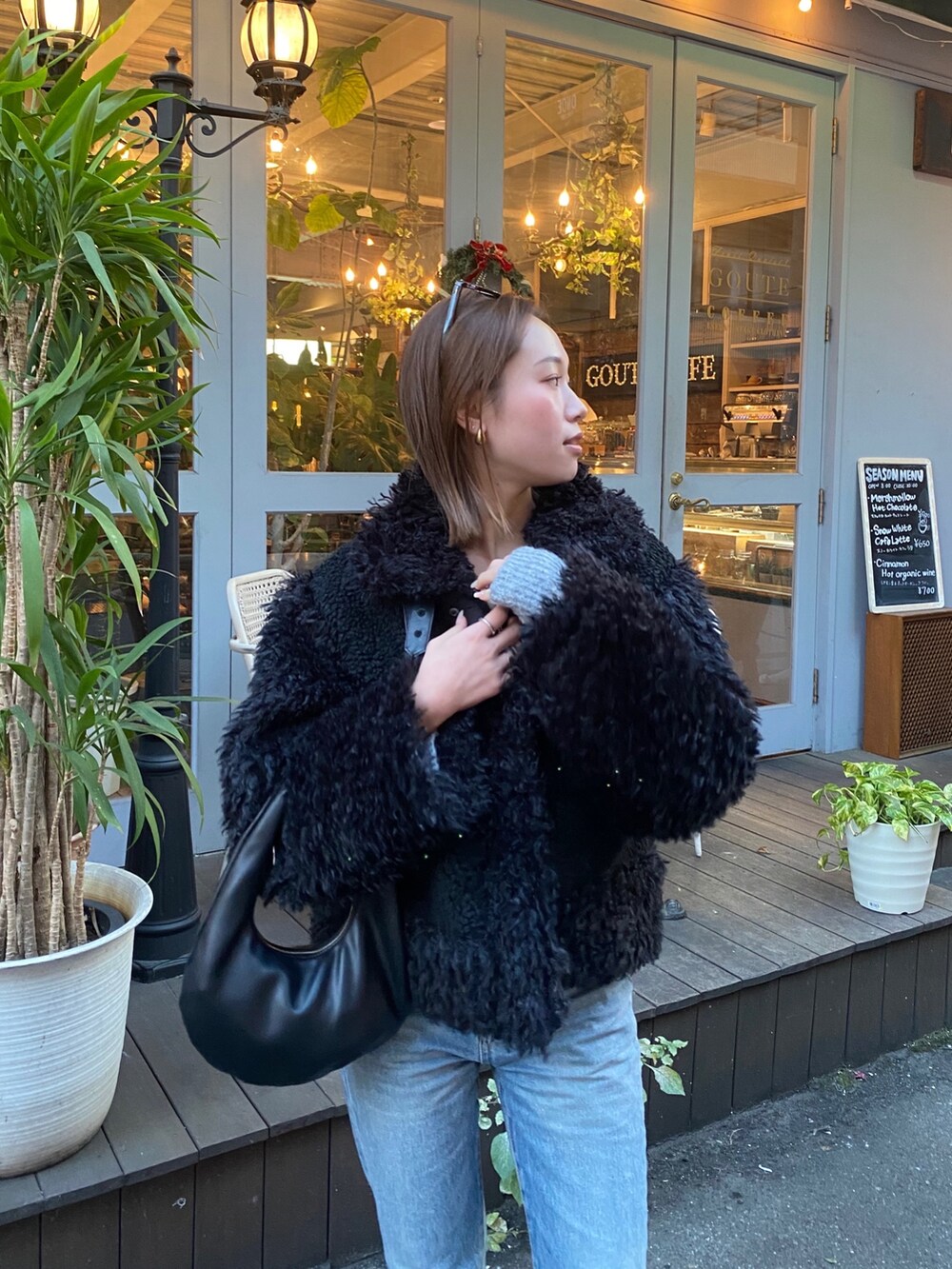 ブラック系のムートンコートを着用したレディースの冬コーディネートの4枚目の写真