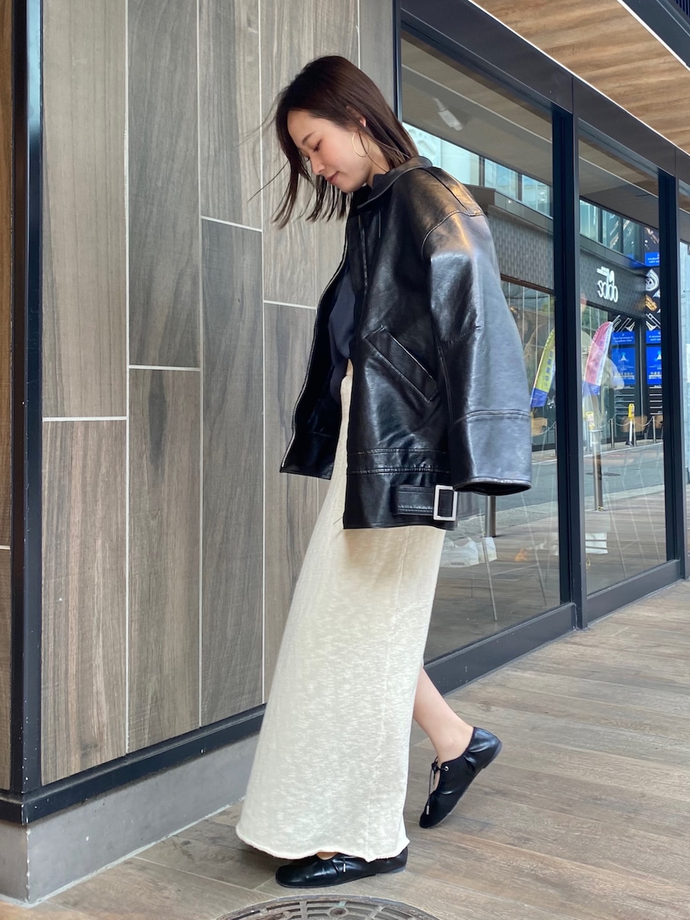 ホワイト系のスカート、ブラック系のブルゾン、グレー系のTシャツ/カットソーを着用したレディースの冬コーディネートの2枚目の写真