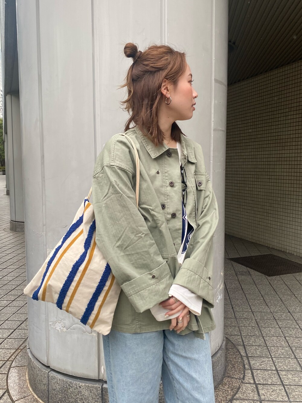 ブルー系のデニムパンツ、グリーン系のミリタリージャケット、ホワイト系のTシャツ/カットソーを着用したレディースの春コーディネートの5枚目の写真