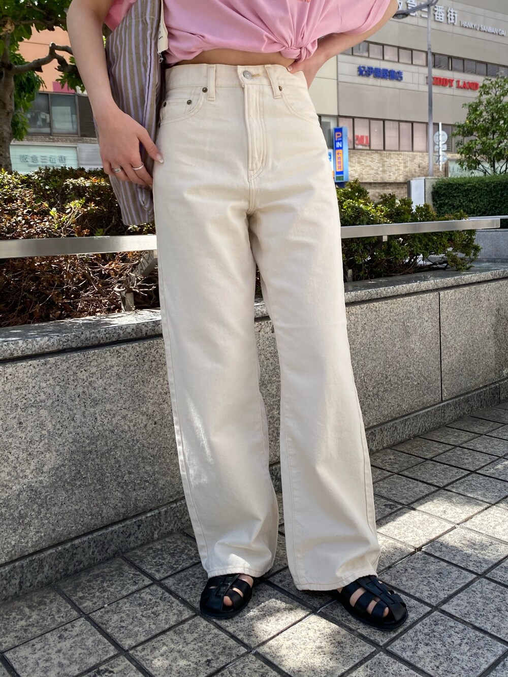 ホワイト系のデニムパンツ、ピンク系のTシャツ/カットソー、ブラック系のサンダルを着用したレディースの春コーディネートの6枚目の写真