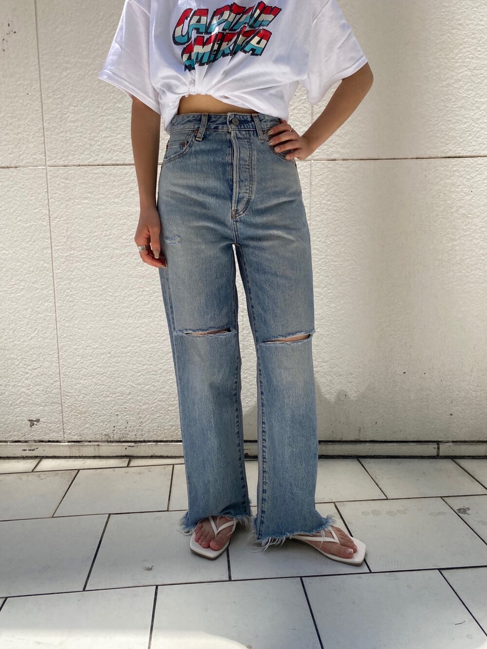 ブルー系のデニムパンツ、ホワイト系のサンダル、ホワイト系のTシャツ/カットソーを着用したレディースの夏コーディネートの4枚目の写真