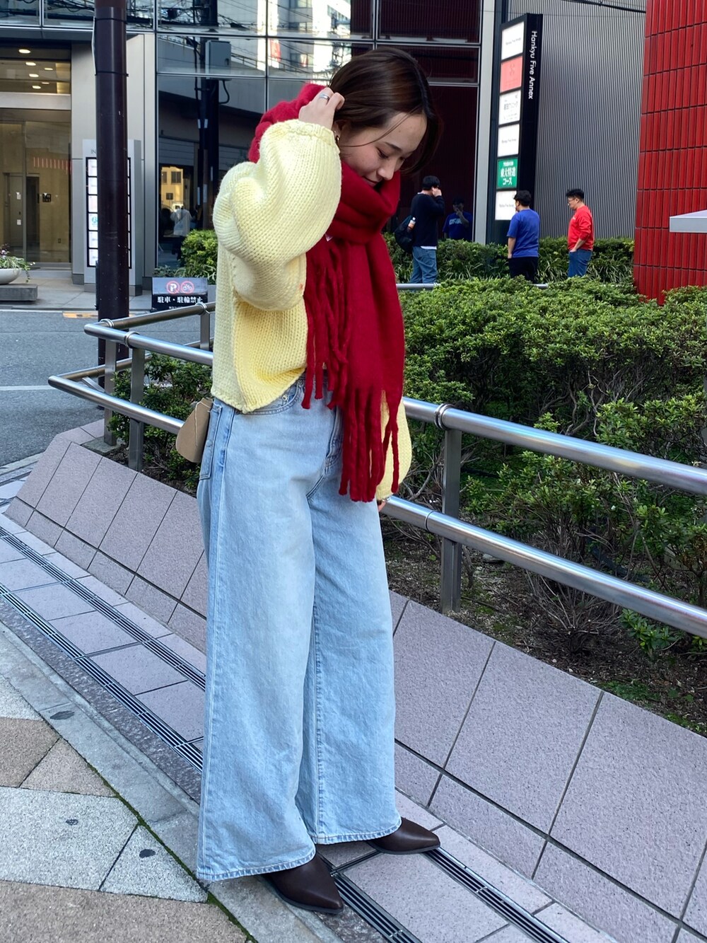 ブルー系のデニムパンツ、イエロー系のニット/セーター、ブラウン系のブーツを着用したレディースの秋コーディネートの2枚目の写真