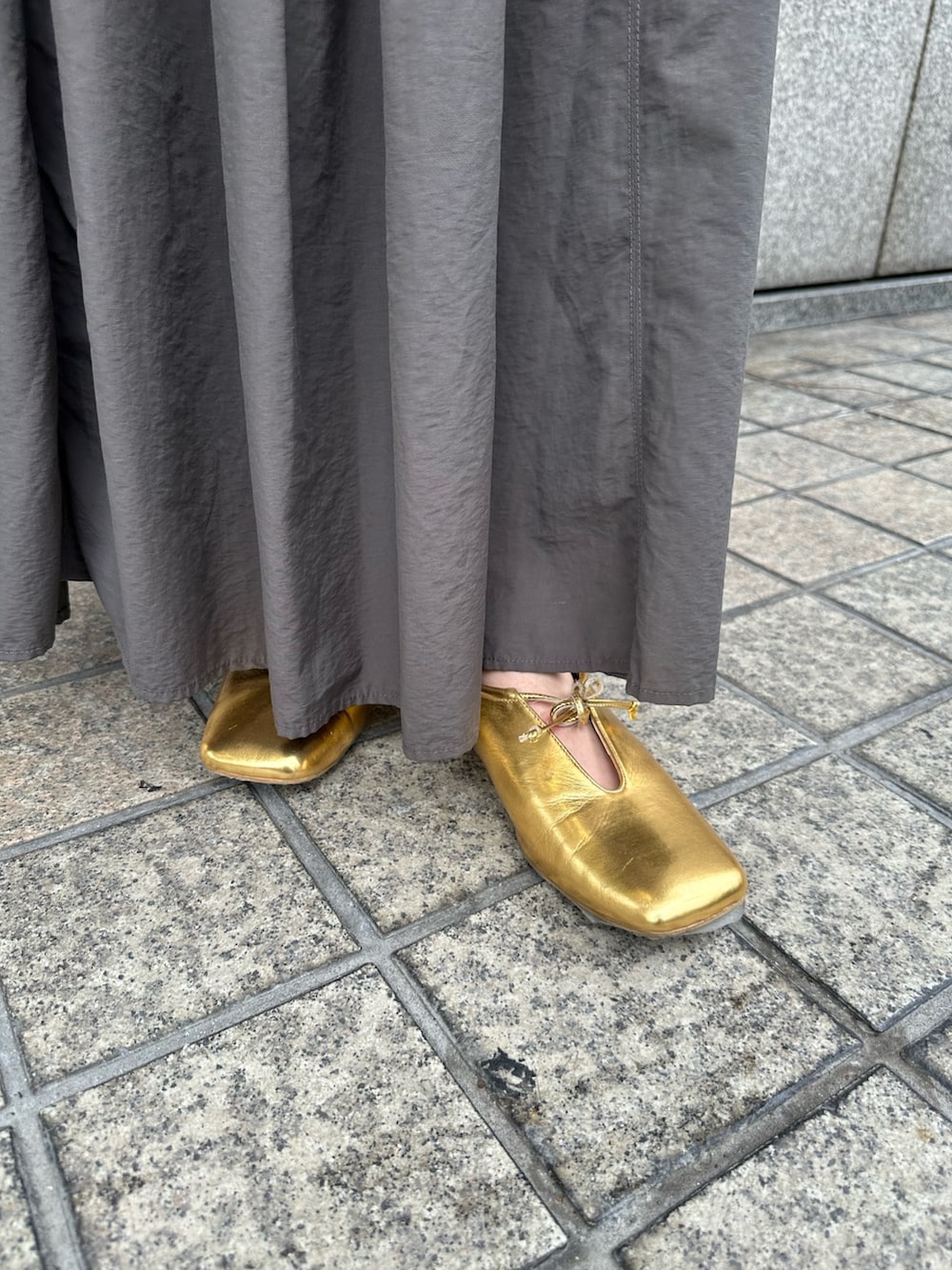 グレー系のスカート、オレンジ系のTシャツ/カットソー、ブラウン系のトレンチコートを着用したレディースの冬コーディネートの5枚目の写真