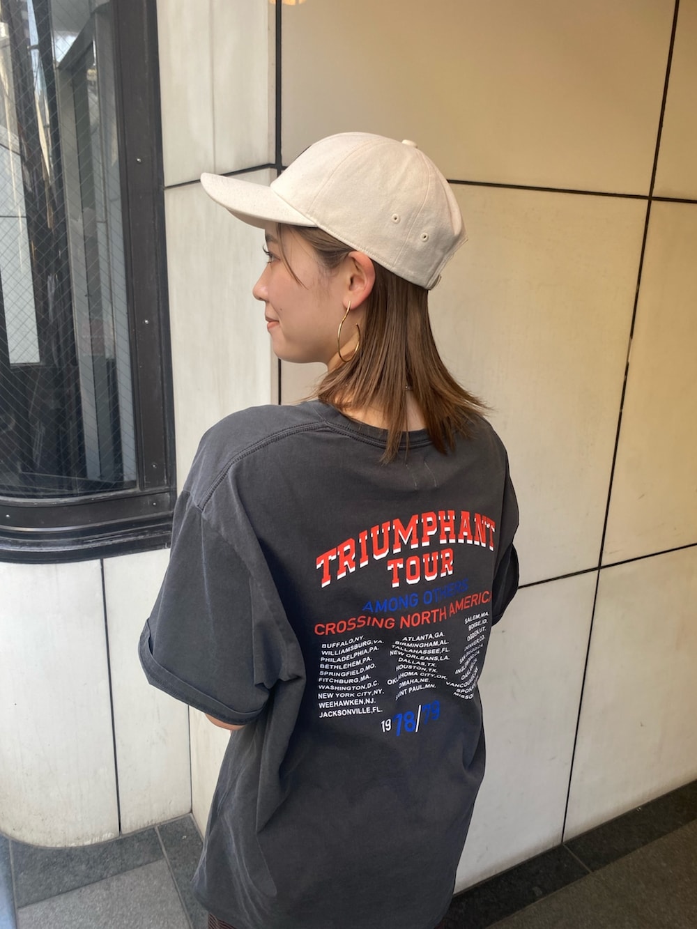 グレー系のTシャツ/カットソー、ブラウン系のワンピース、ホワイト系のキャップを着用したレディースの春コーディネートの3枚目の写真