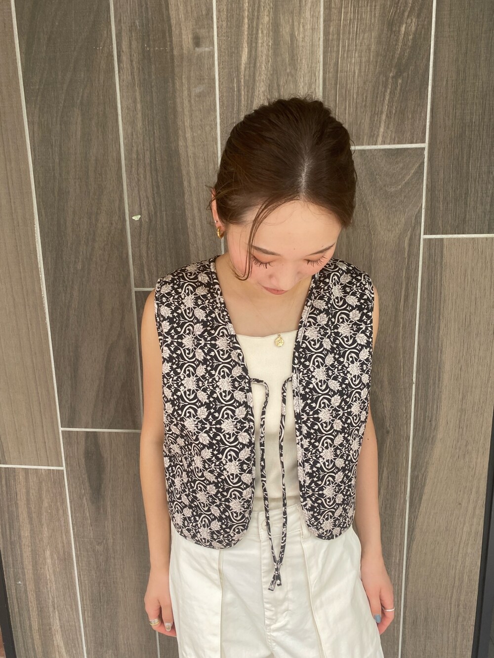 ホワイト系のカーゴパンツ、ブラック系のベスト、ホワイト系のキャミソールを着用したレディースの夏コーディネートの3枚目の写真