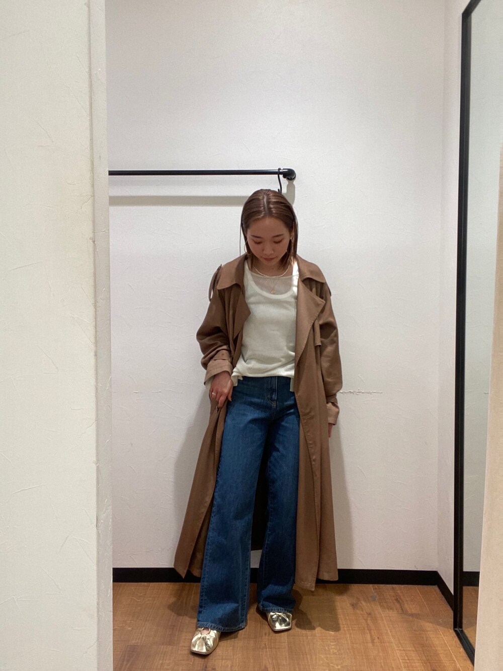 イエロー系のトレンチコート、ブルー系のデニムパンツ、ゴールド系のパンプスを着用したレディースの春コーディネートの2枚目の写真