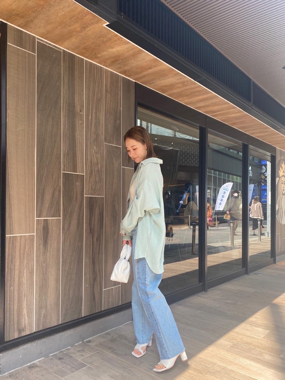 グリーン系のシャツ/ブラウス、ブルー系のデニムパンツ、ホワイト系のハンドバッグを着用したレディースの春コーディネートの2枚目の写真