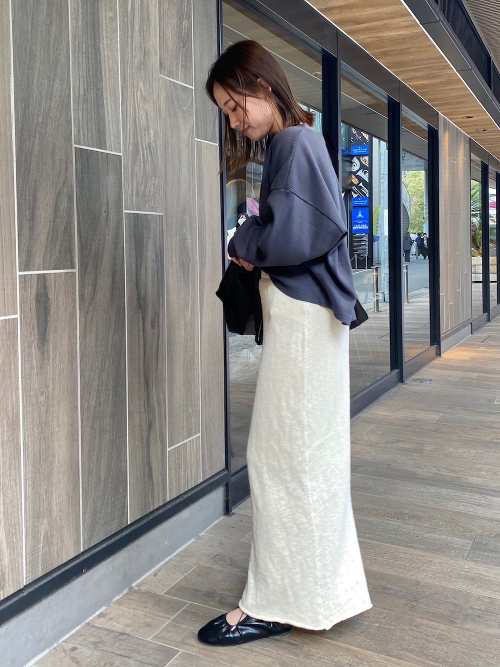 ホワイト系のスカート、ブラック系のブルゾン、グレー系のTシャツ/カットソーを着用したレディースの冬コーディネートの4枚目の写真