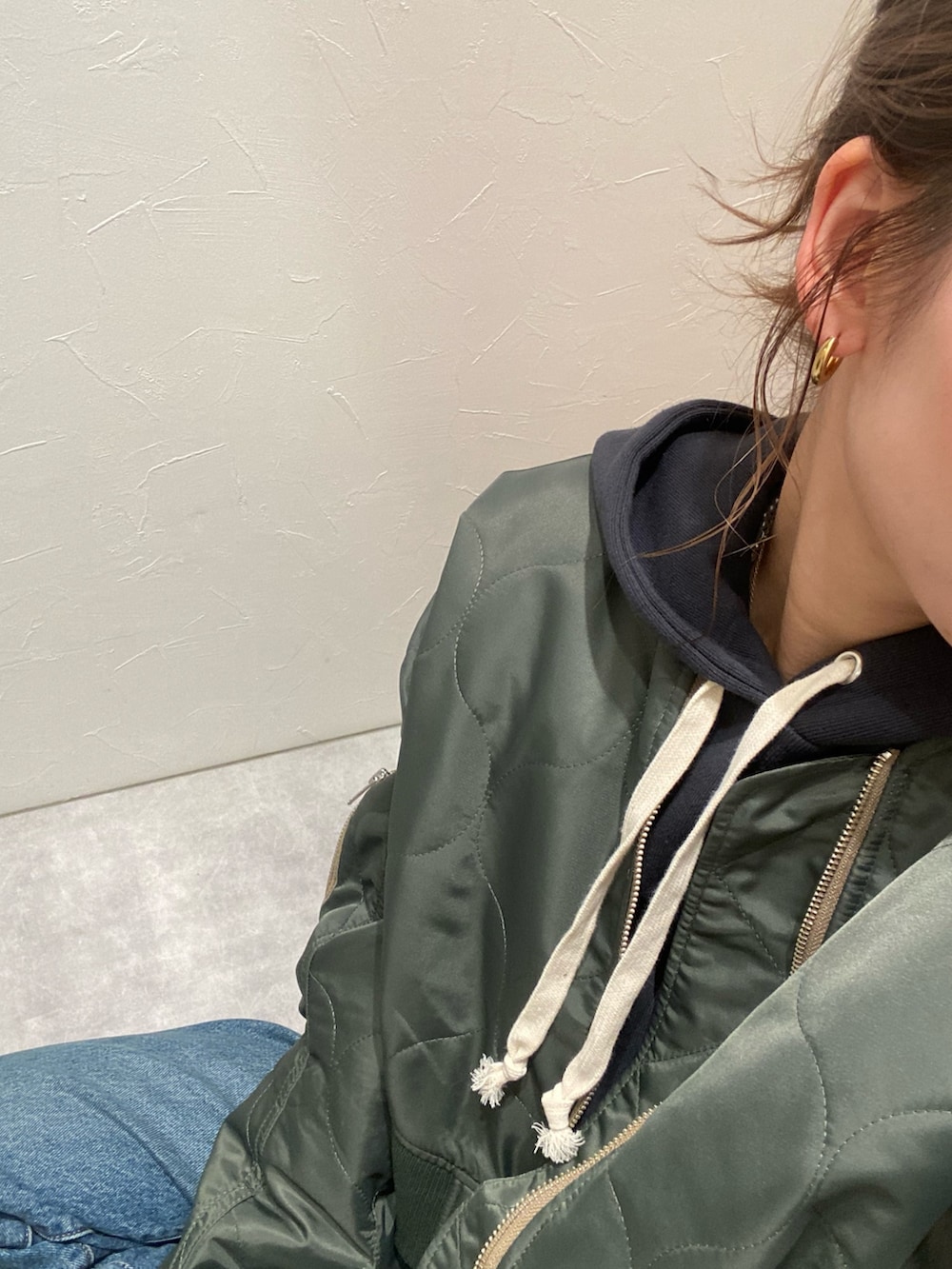 ベージュ系のブルゾン、グレー系のパーカー、ブルー系のデニムパンツを着用したレディースの秋コーディネートの3枚目の写真