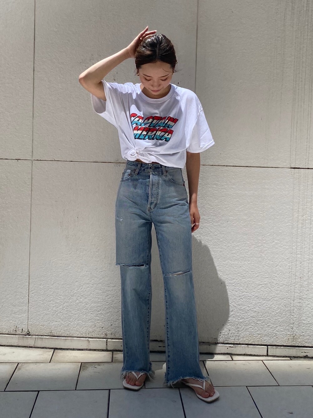 ブルー系のデニムパンツ、ホワイト系のサンダル、ホワイト系のTシャツ/カットソーを着用したレディースの夏コーディネートの2枚目の写真