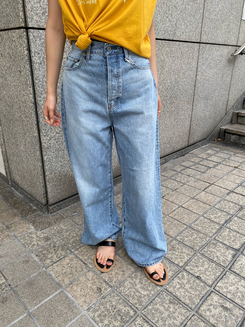 ブルー系のデニムパンツ、イエロー系のTシャツ/カットソー、ブラック系のサンダルを着用したレディースの夏コーディネートの5枚目の写真