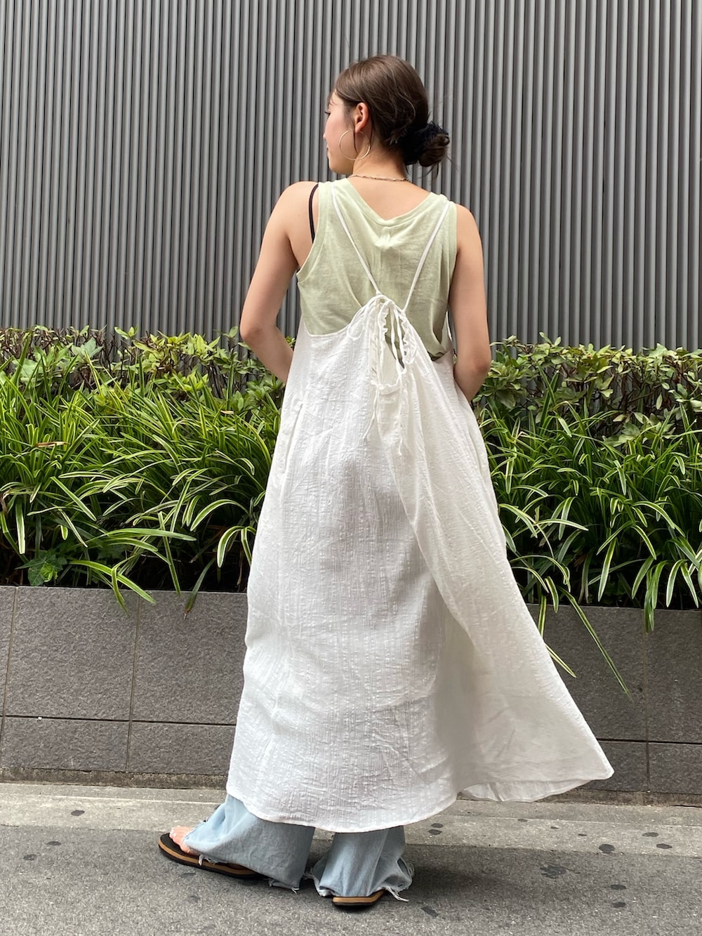 ホワイト系のワンピース、グリーン系のタンクトップ、ブルー系のデニムパンツを着用したレディースの夏コーディネートの3枚目の写真