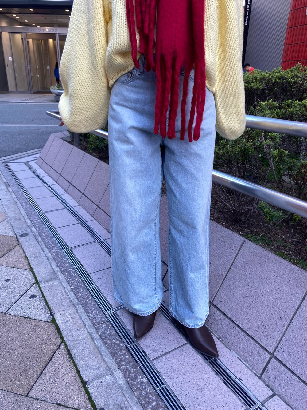 ブルー系のデニムパンツ、イエロー系のニット/セーター、ブラウン系のブーツを着用したレディースの秋コーディネートの9枚目の写真