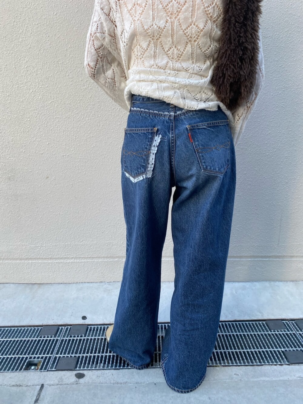 ブルー系のデニムパンツ、ホワイト系のニット/セーター、ブラウン系のハンドバッグを着用したレディースの夏コーディネートの5枚目の写真