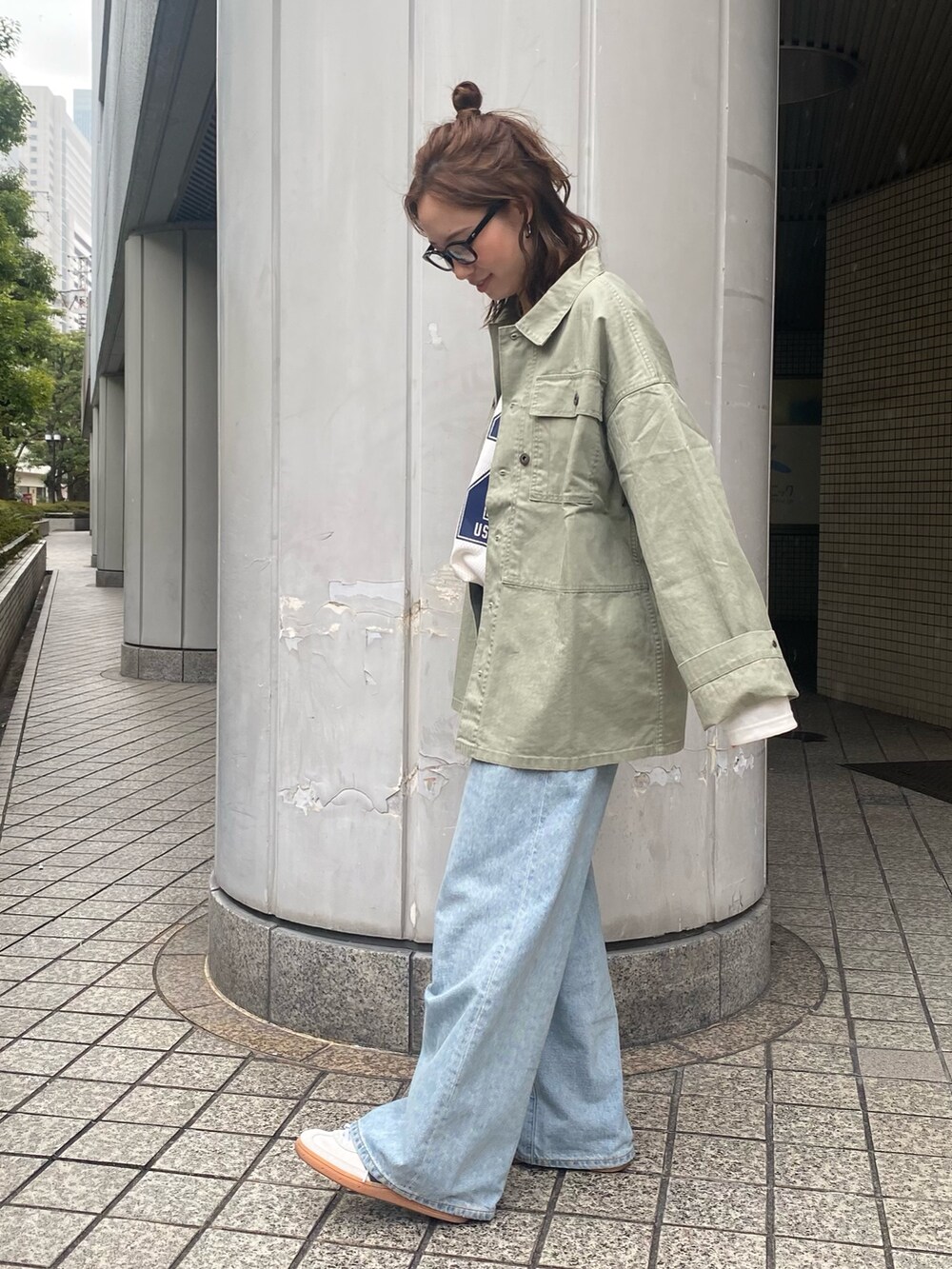 ブルー系のデニムパンツ、グリーン系のミリタリージャケット、ホワイト系のTシャツ/カットソーを着用したレディースの春コーディネートの2枚目の写真