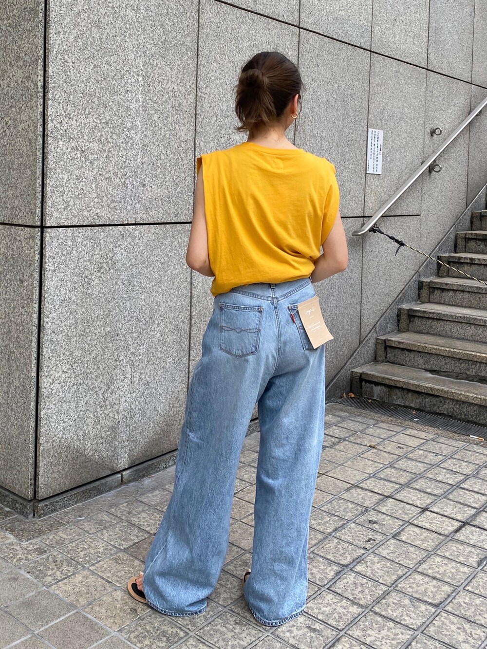 ブルー系のデニムパンツ、イエロー系のTシャツ/カットソー、ブラック系のサンダルを着用したレディースの夏コーディネートの3枚目の写真