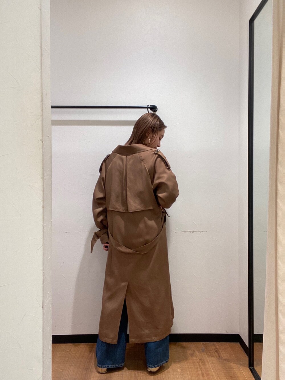イエロー系のトレンチコート、ブルー系のデニムパンツ、ゴールド系のパンプスを着用したレディースの春コーディネートの4枚目の写真