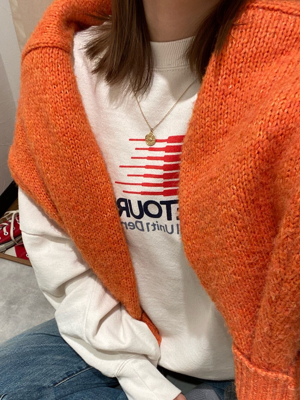 ホワイト系のスウェット、ブルー系のデニムパンツ、オレンジ系のニット/セーターを着用したレディースの冬コーディネートの5枚目の写真