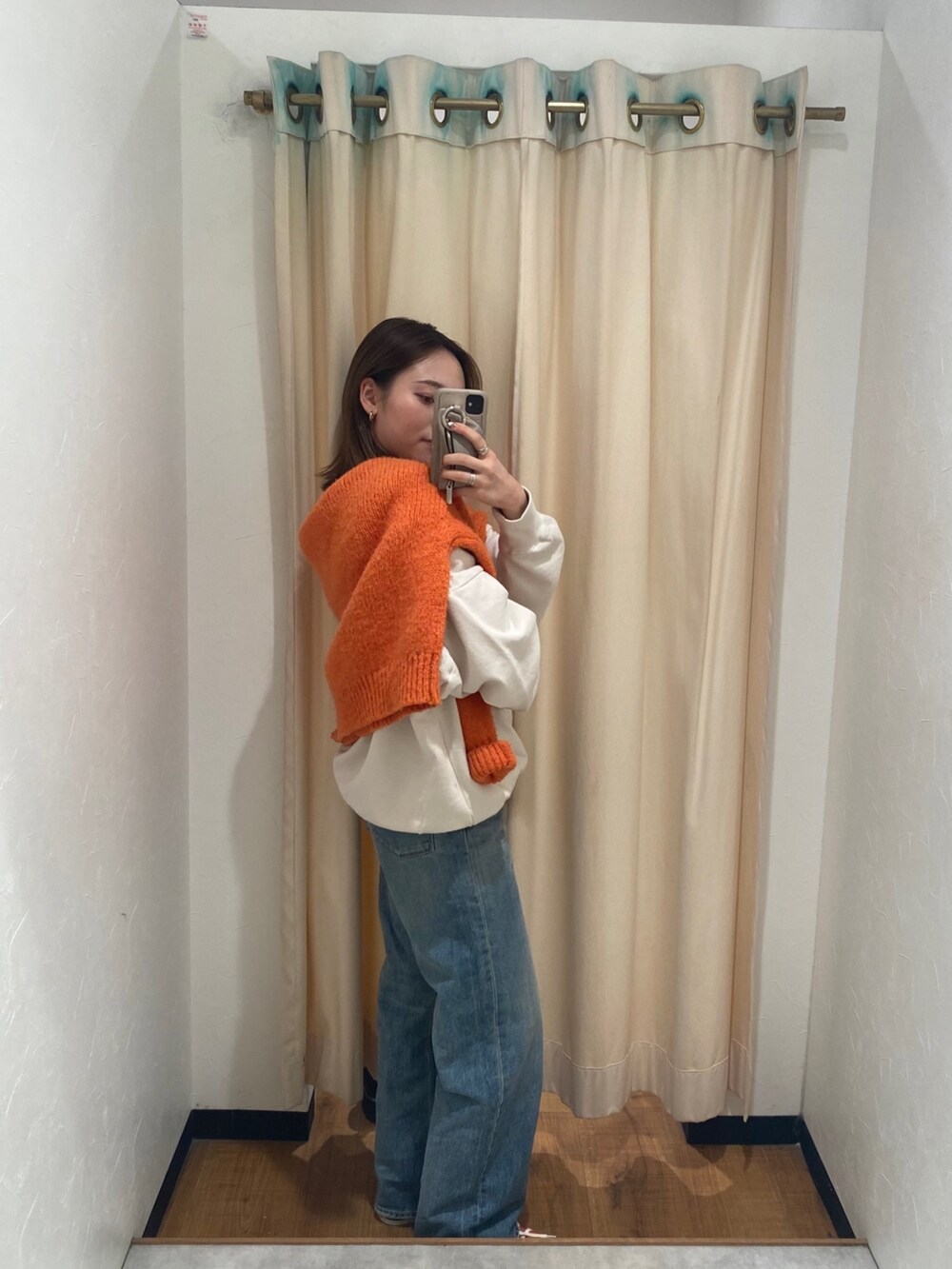 ホワイト系のスウェット、ブルー系のデニムパンツ、オレンジ系のニット/セーターを着用したレディースの冬コーディネートの3枚目の写真