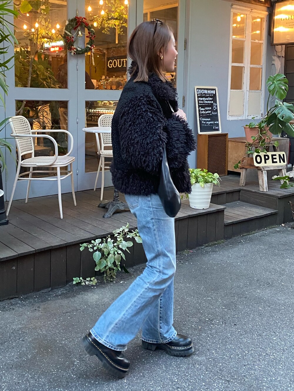ブラック系のムートンコートを着用したレディースの冬コーディネートの2枚目の写真