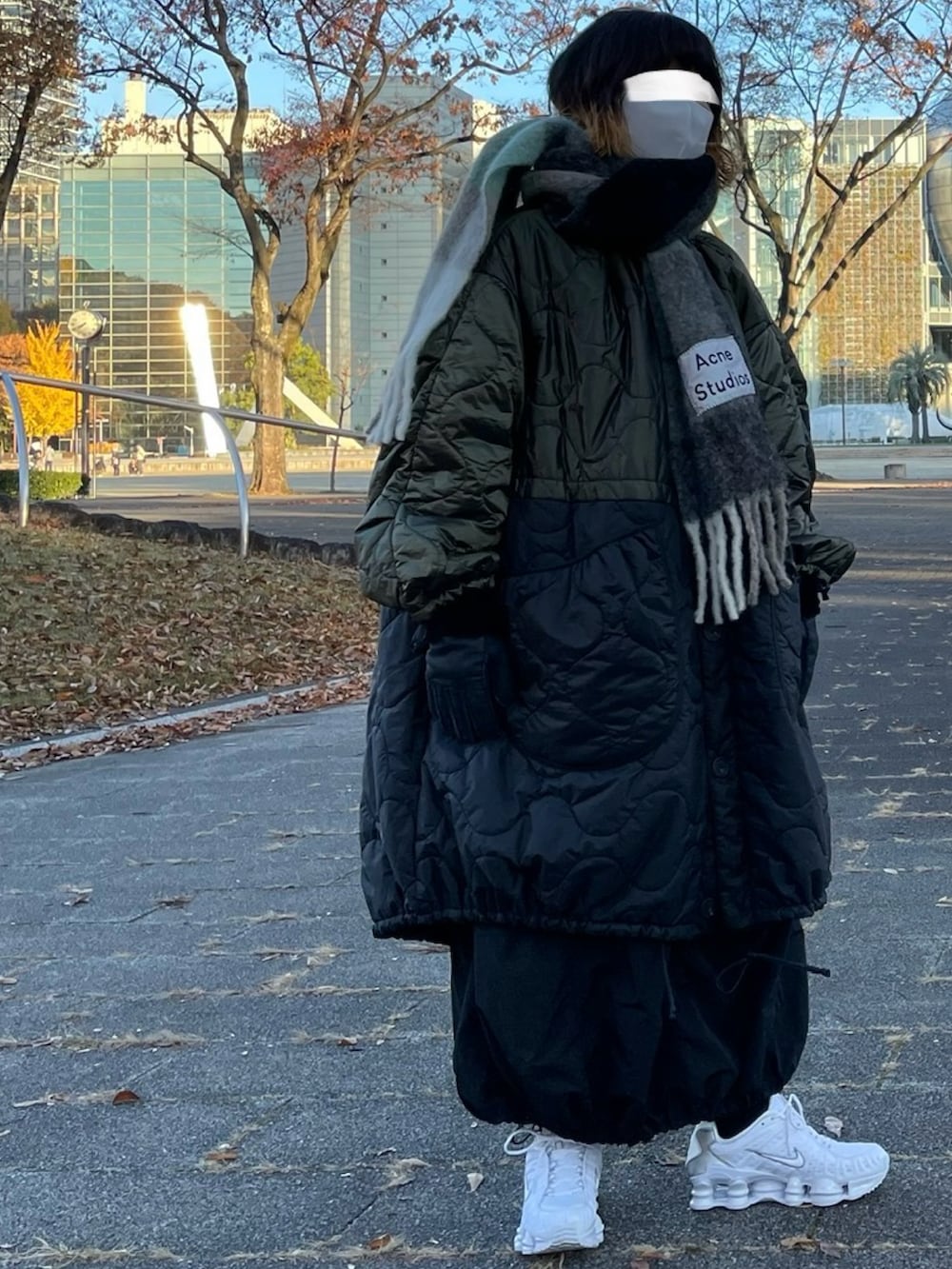 ブラック系のその他アウター、ホワイト系のスニーカー、グリーン系のマフラーを着用したレディースの冬コーディネートの2枚目の写真