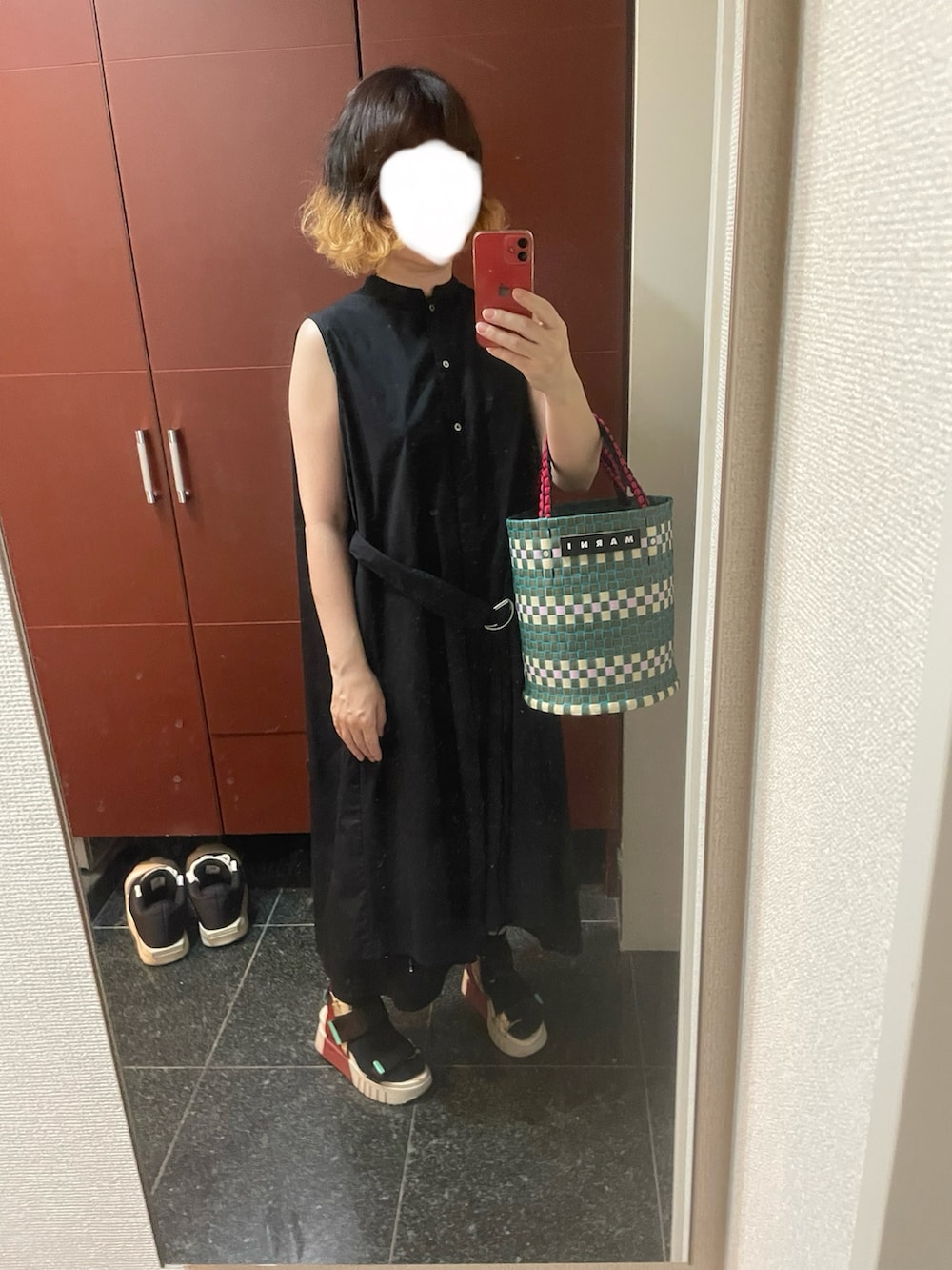 ホワイト系のサンダル、ブラック系のワンピース、グリーン系のかごバッグを着用したレディースの夏コーディネートの2枚目の写真