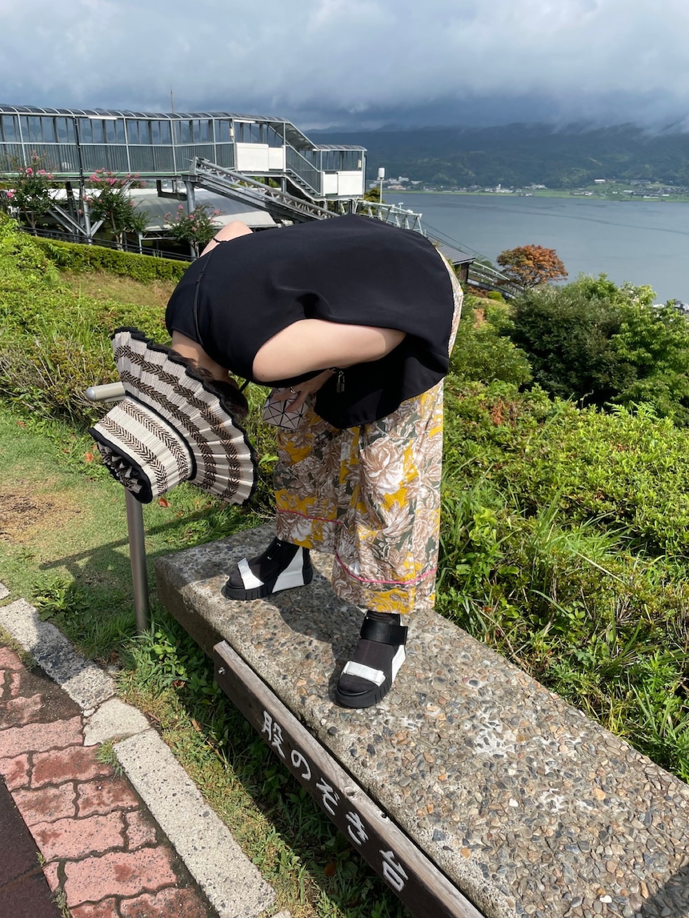 ブラック系のタンクトップ、イエロー系のパンツ、ホワイト系のショルダーバッグを着用したレディースの春コーディネートの2枚目の写真