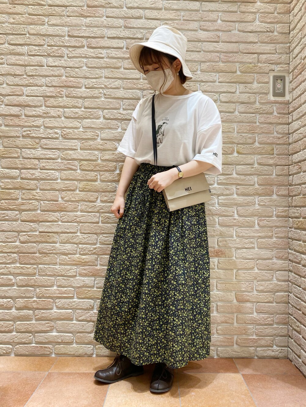 ホワイト系のTシャツ/カットソー、ベージュ系のマウンテンパーカー、ブラック系のスカートを着用したレディースの春コーディネートの2枚目の写真