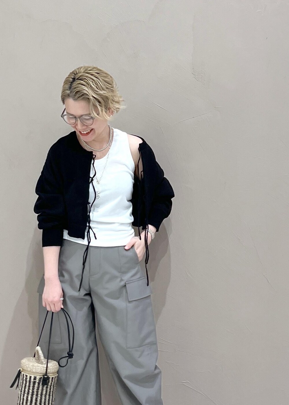 ブラック系のニット/セーター、グレー系のカーゴパンツ、ホワイト系のショルダーバッグを着用したレディースの春コーディネートの5枚目の写真