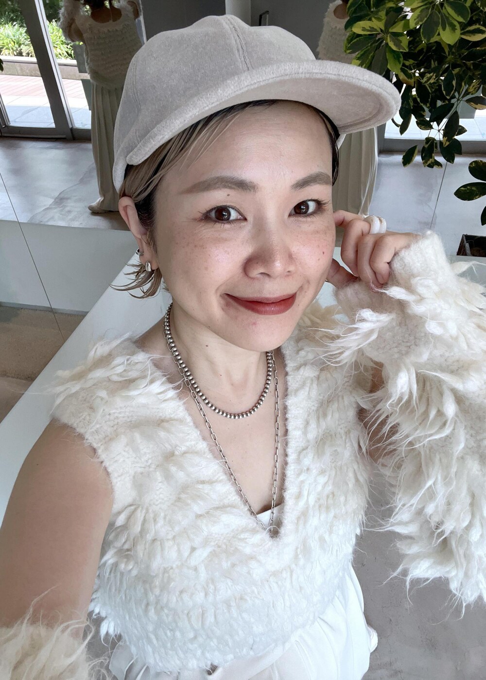 グレー系のショルダーバッグ、ホワイト系のベスト、ホワイト系のキャップを着用したレディースの秋コーディネートの8枚目の写真