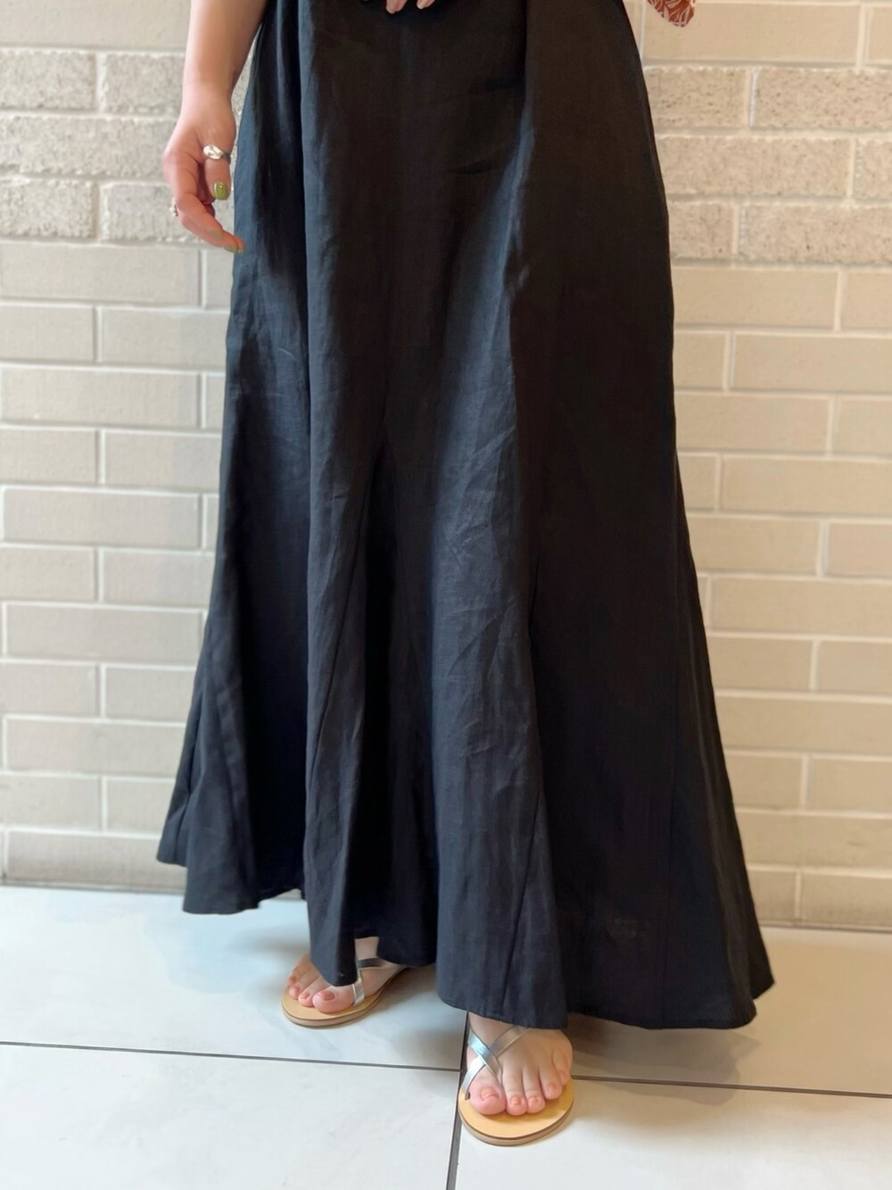 オレンジ系のシャツ/ブラウス、ブラック系のワンピース、シルバー系のサンダルを着用したレディースの夏コーディネートの4枚目の写真