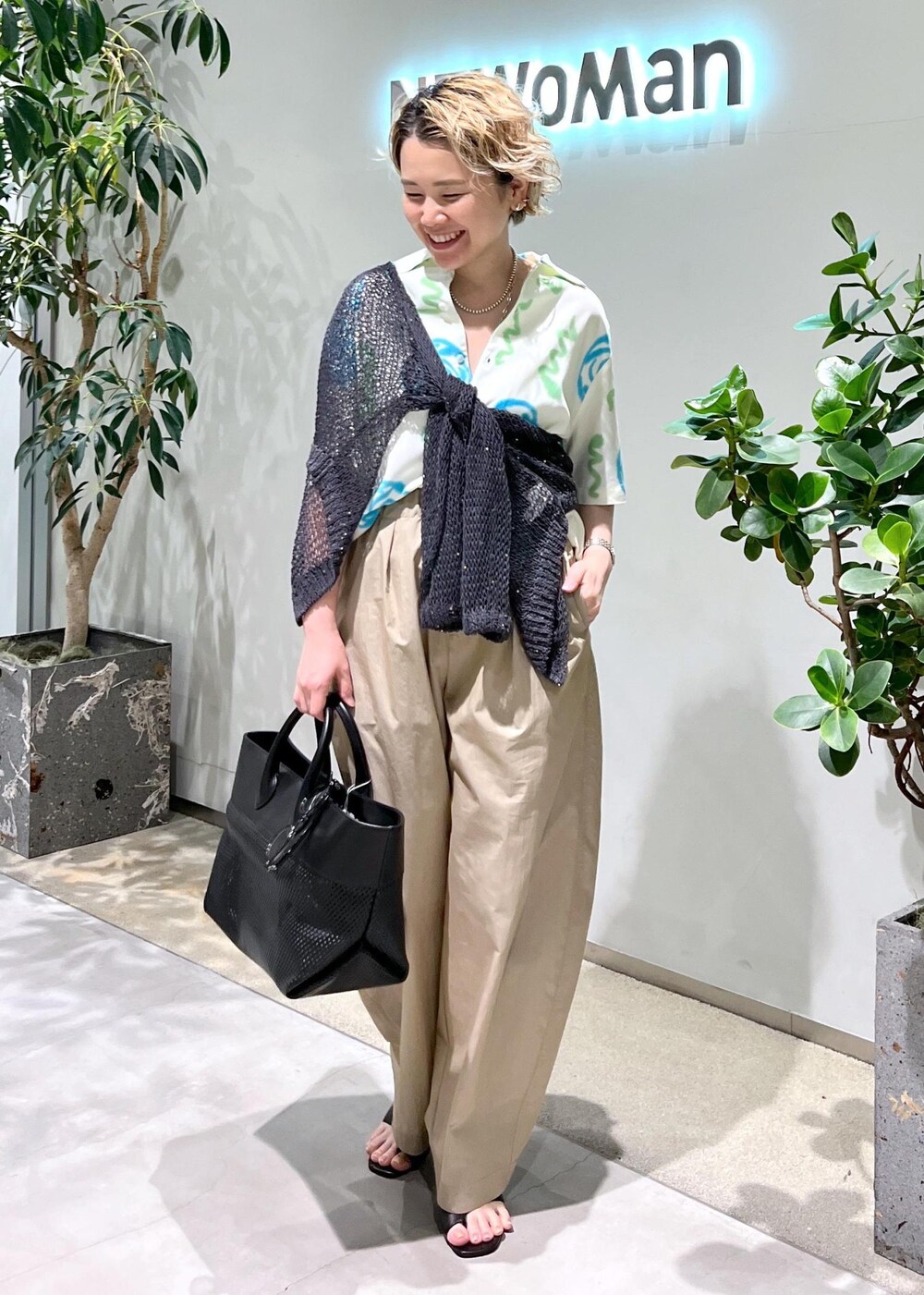 ブラック系のトートバッグ、ブラック系のサンダル、グレー系のカーディガン/ボレロを着用したレディースの春コーディネートの3枚目の写真