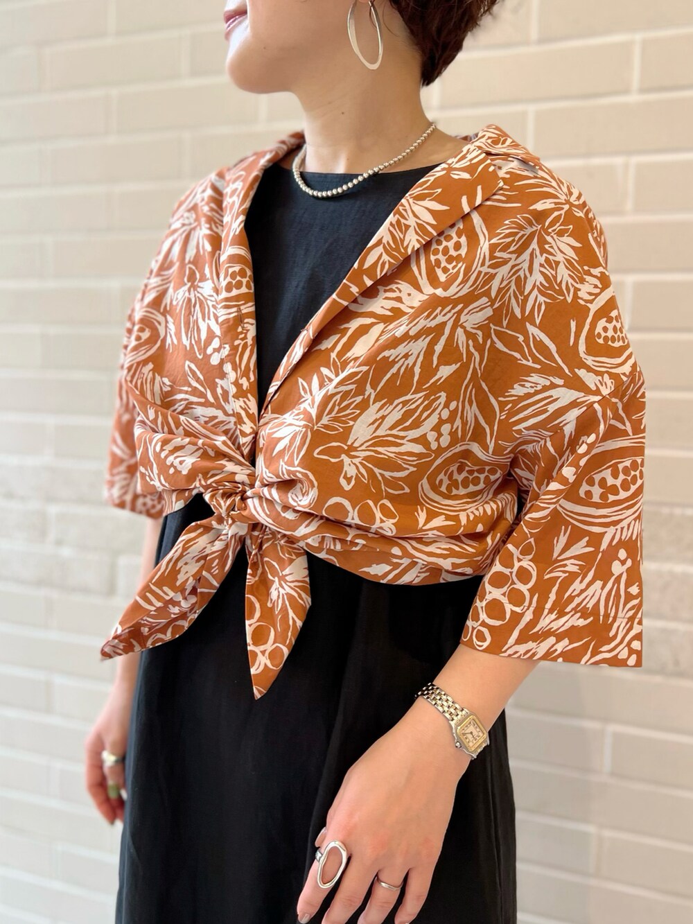 オレンジ系のシャツ/ブラウス、ブラック系のワンピース、シルバー系のサンダルを着用したレディースの夏コーディネートの3枚目の写真