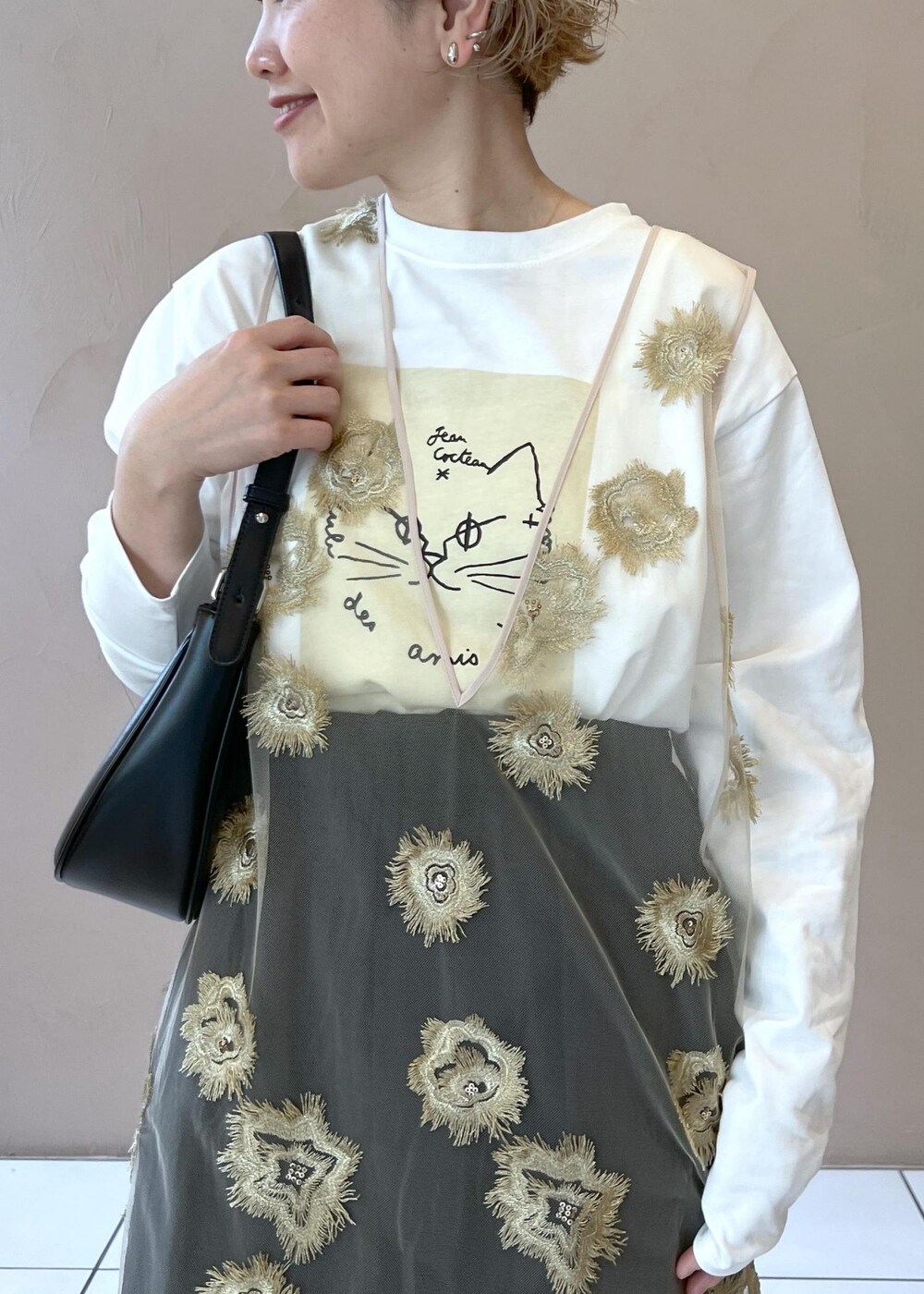 ゴールド系のワンピース、ベージュ系のダウンジャケット/コート、ホワイト系のTシャツ/カットソーを着用したレディースの秋コーディネートの9枚目の写真