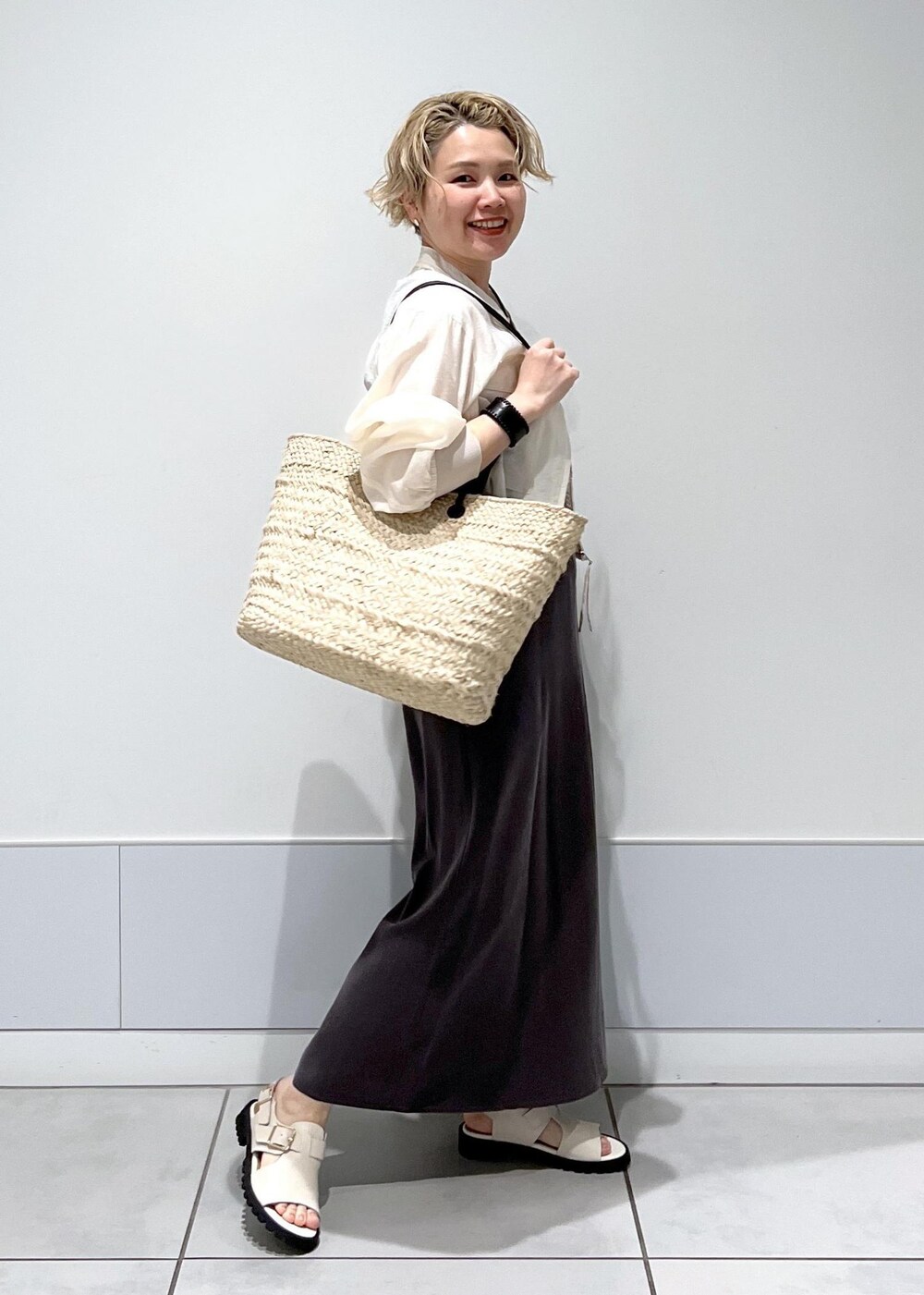 ホワイト系のサンダル、ホワイト系のブルゾン、グレー系のワンピースを着用したレディースの春コーディネートの5枚目の写真