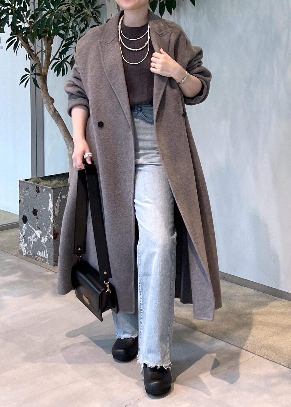 グレー系のニット/セーター、ブラック系のショルダーバッグ、ブラウン系のその他アウターを着用したレディースの秋コーディネートの5枚目の写真