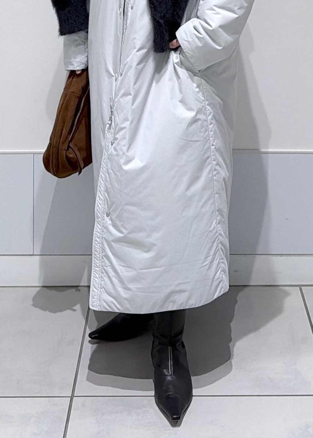 ブラック系のスカート、ブラウン系のハンドバッグ、グレー系のダウンジャケット/コートを着用したレディースの秋コーディネートの6枚目の写真