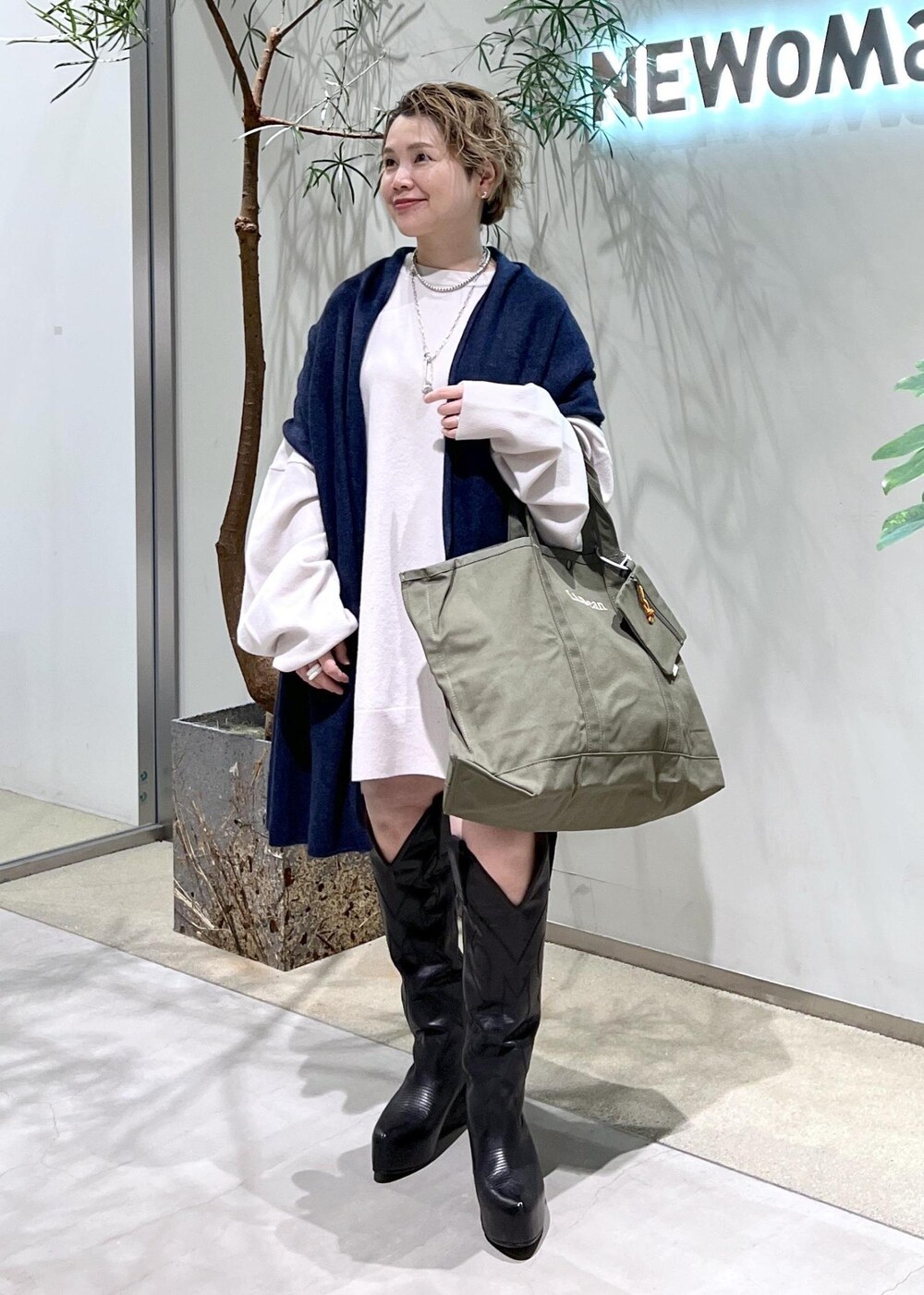 ブラック系のブーツ、グリーン系のトートバッグを着用したレディースの秋コーディネートの8枚目の写真