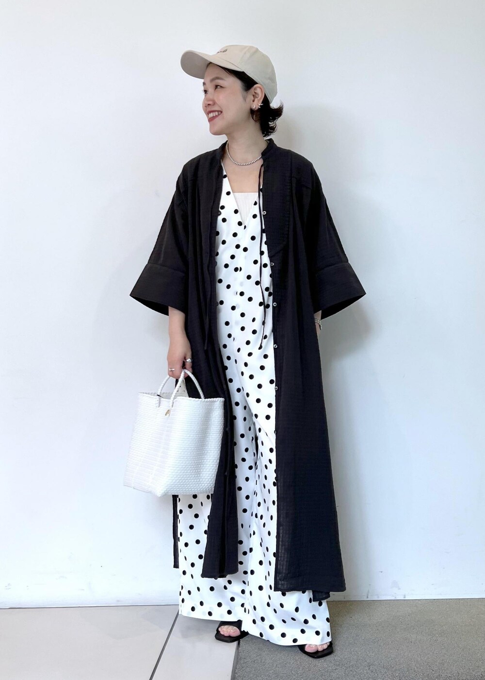 ホワイト系のつなぎ/オールインワン、ホワイト系のかごバッグ、ブラック系のシャツ/ブラウスを着用したレディースの夏コーディネートの2枚目の写真