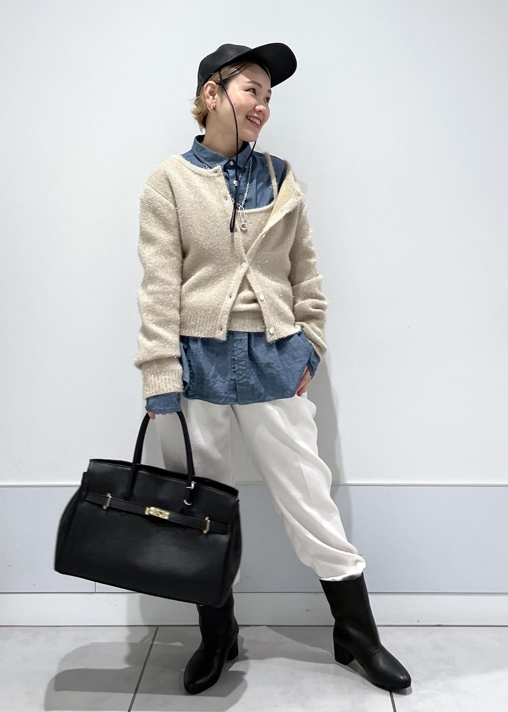 ゴールド系のカーディガン/ボレロ、ブラック系のハンドバッグ、ブラック系のブーツを着用したレディースの秋コーディネートの4枚目の写真