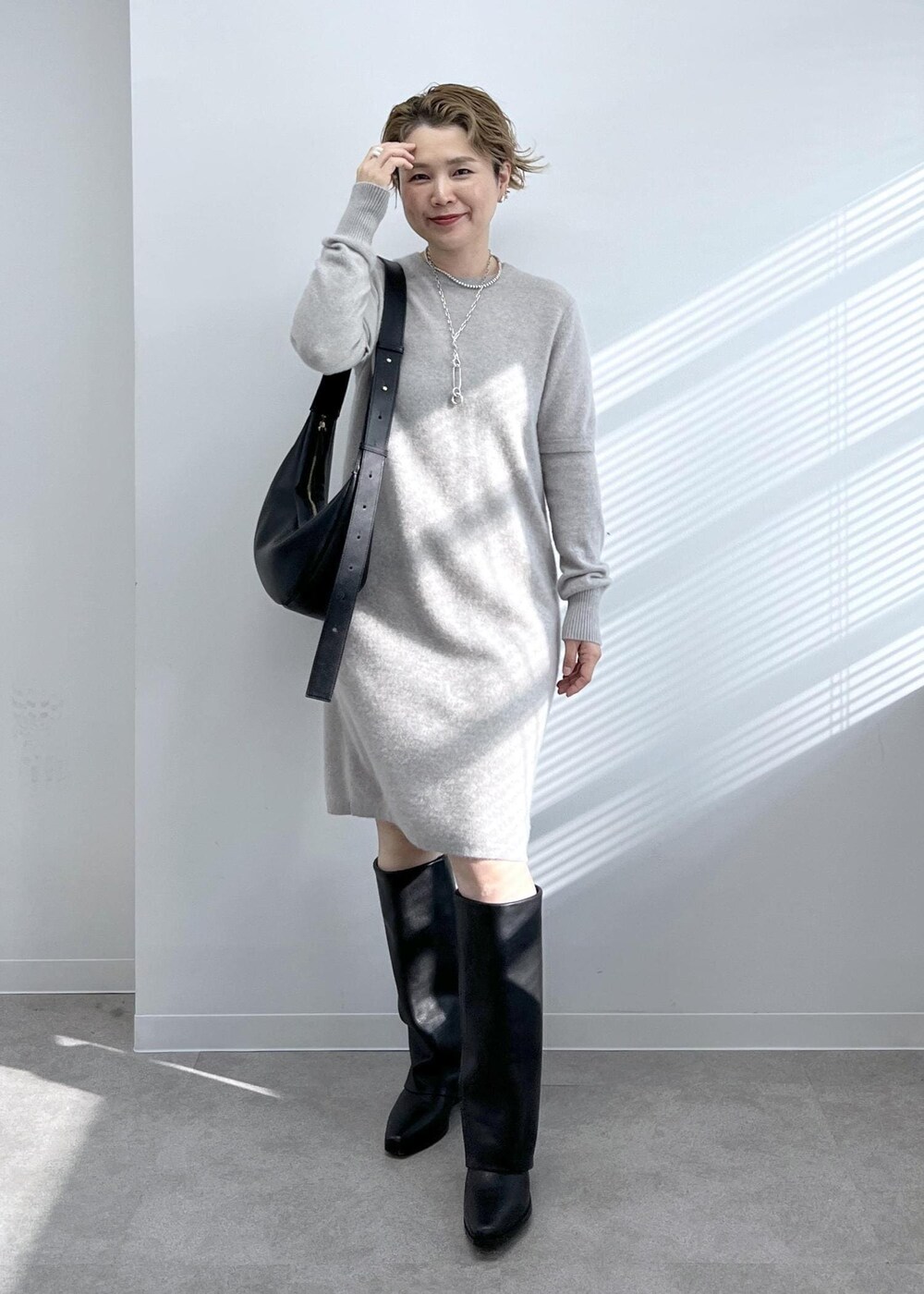 ブラック系のショルダーバッグ、ブラック系のブーツ、ベージュ系のワンピースを着用したレディースの秋コーディネートの6枚目の写真