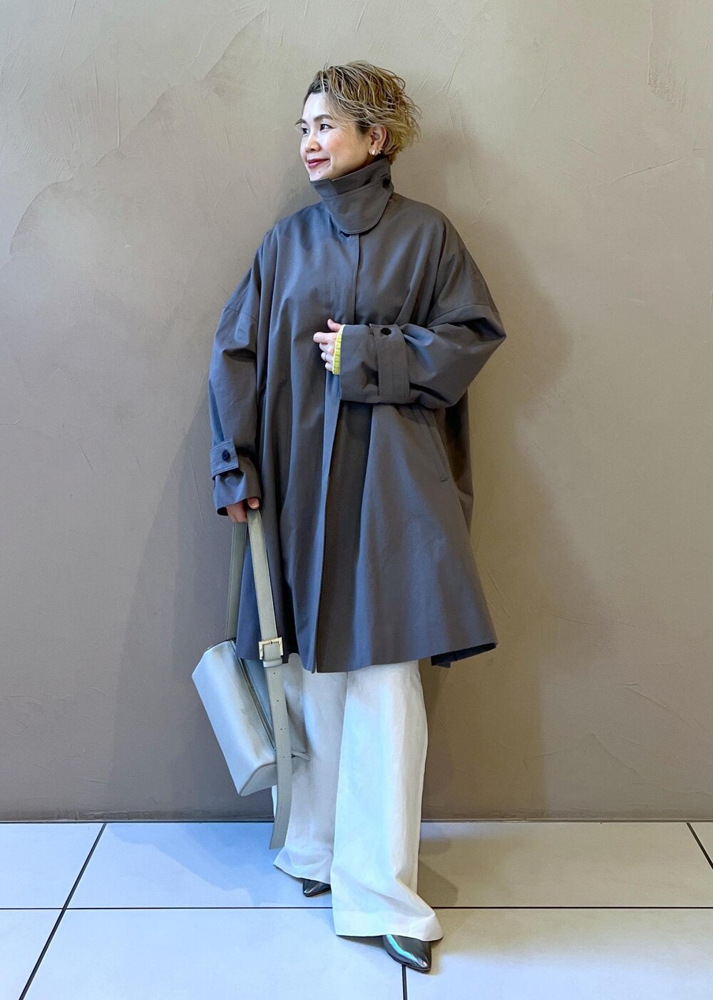 シルバー系のショルダーバッグ、イエロー系のカーディガン/ボレロ、ホワイト系のサロペット/オーバーオールを着用したレディースの冬コーディネートの5枚目の写真