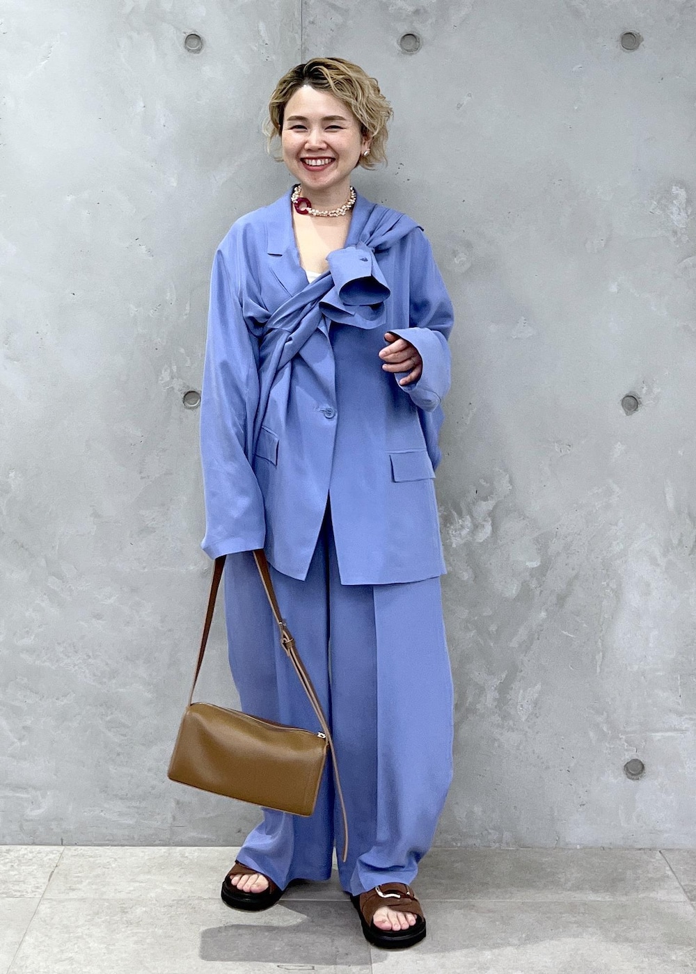 ブラウン系のショルダーバッグ、ブラウン系のサンダル、ブルー系のテーラードジャケットを着用したレディースの冬コーディネートの3枚目の写真