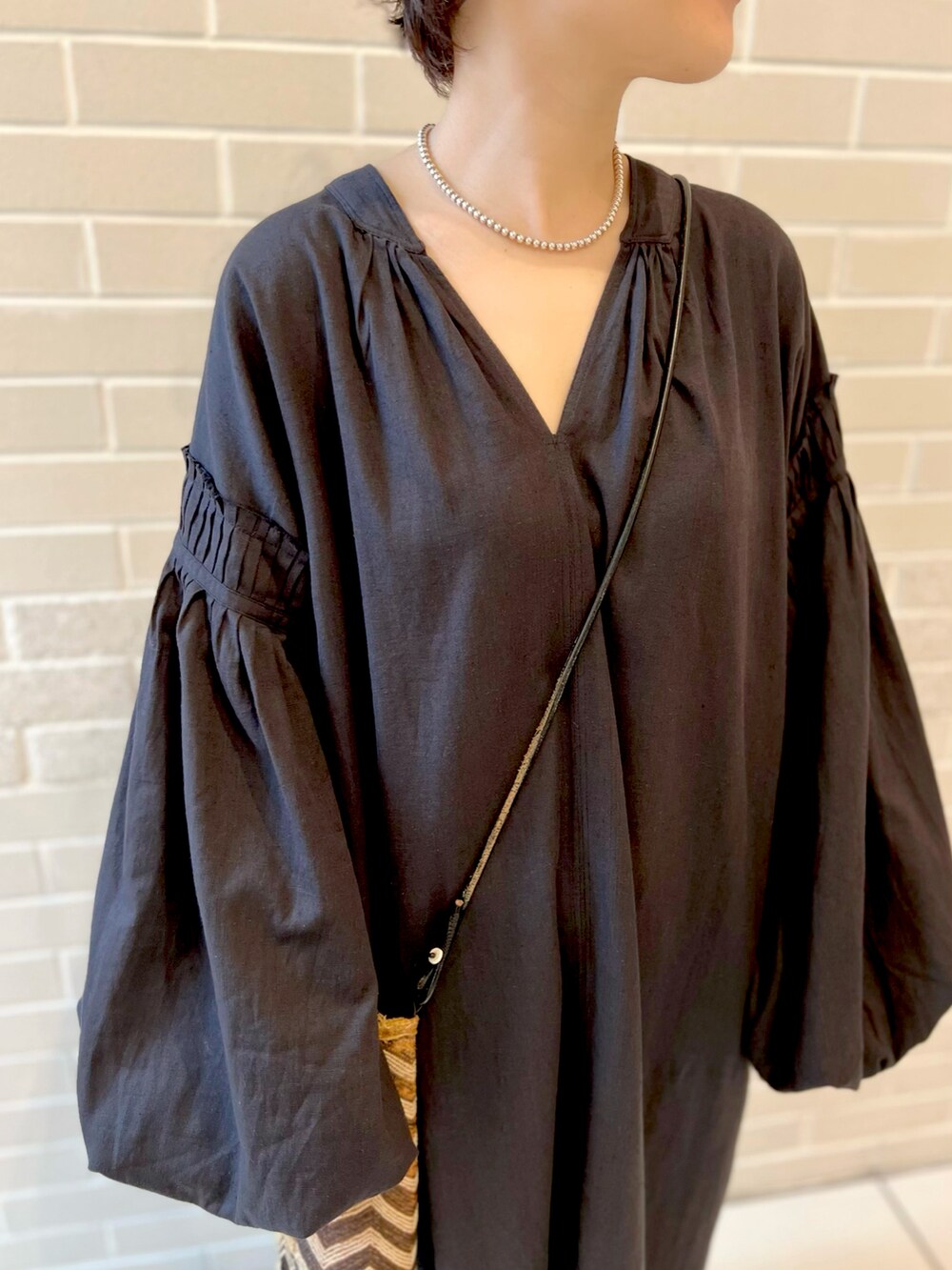 ブラック系のワンピース、ベージュ系のワンピース、ブラック系のスニーカーを着用したレディースの春コーディネートの4枚目の写真