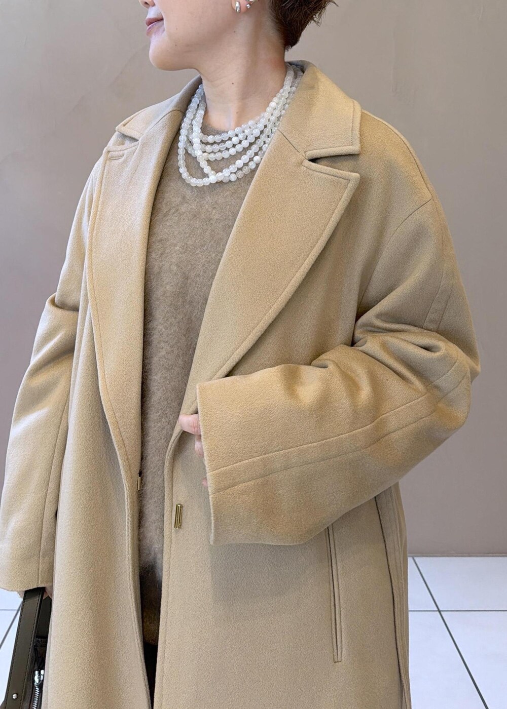 イエロー系のトレンチコート、ゴールド系のその他パンツ、ベージュ系のニット/セーターを着用したレディースの冬コーディネートの8枚目の写真