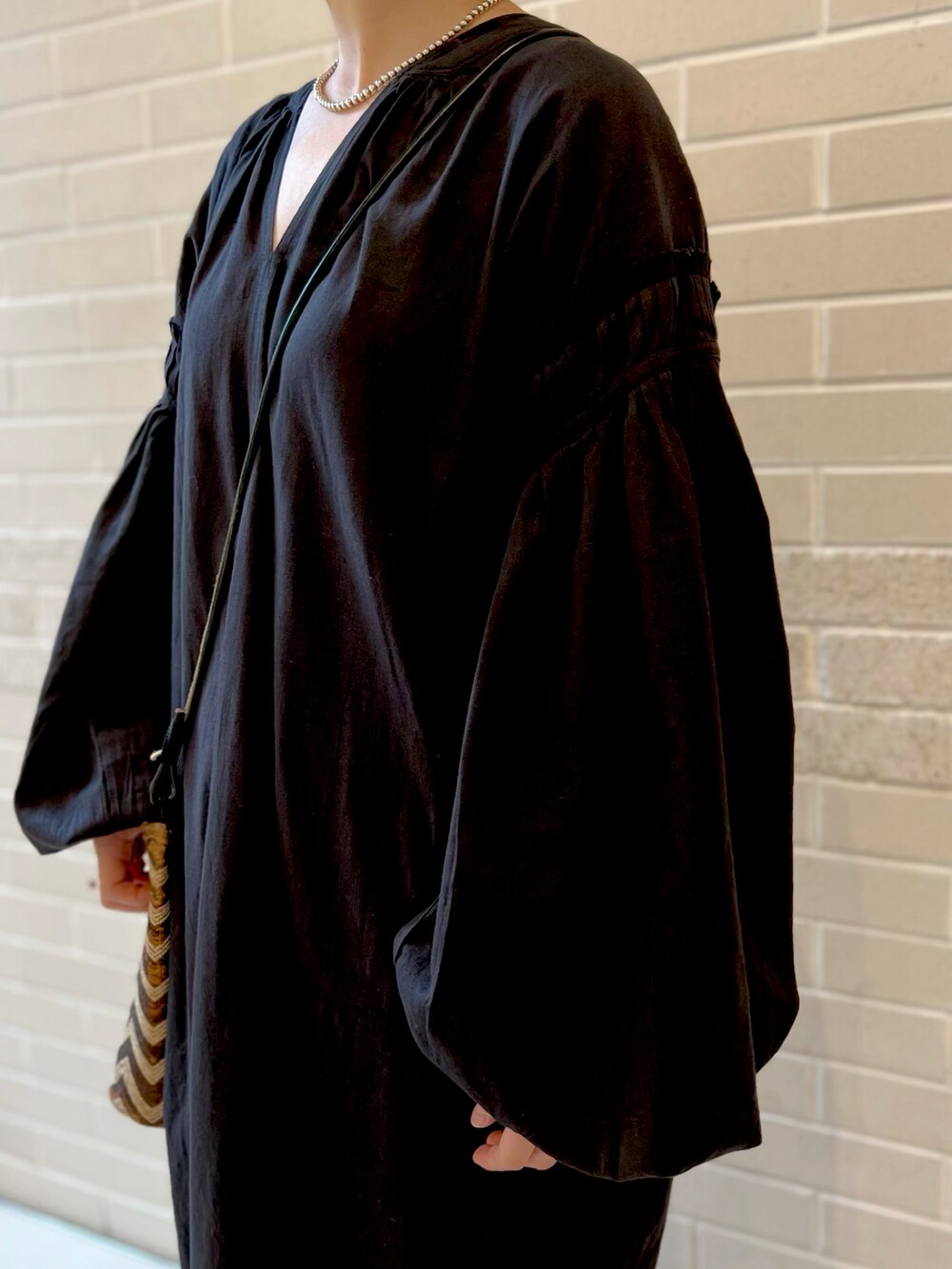 ブラック系のワンピース、ベージュ系のワンピース、ブラック系のスニーカーを着用したレディースの春コーディネートの3枚目の写真