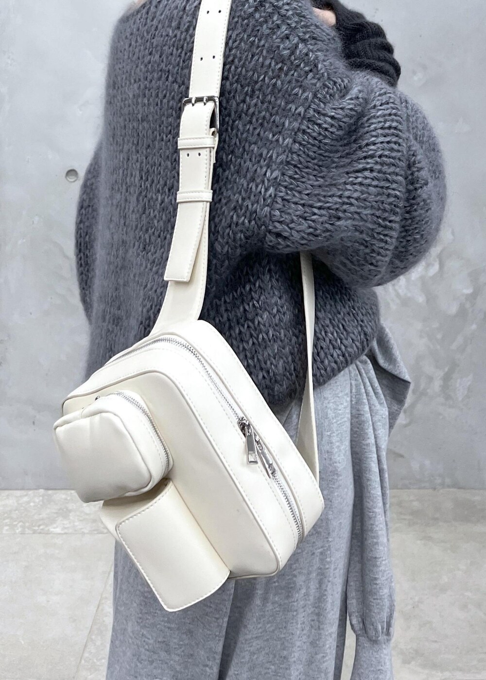 グレー系のニット/セーター、ホワイト系のボディバッグ/ウエストポーチ、グレー系の手袋を着用したレディースの秋コーディネートの8枚目の写真