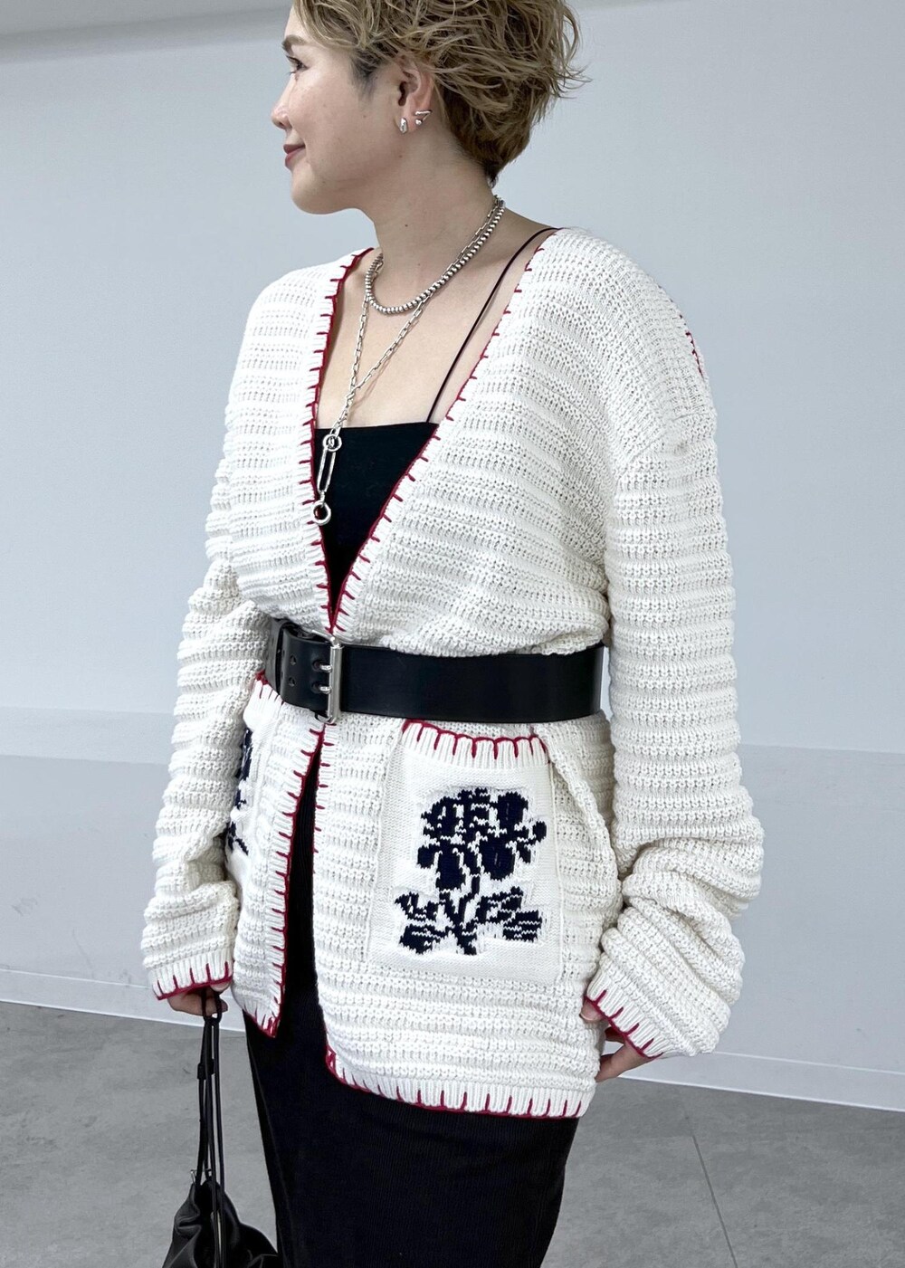 グレー系のスカート、ホワイト系のニット/セーター、レッド系のブーツを着用したレディースの秋コーディネートの6枚目の写真