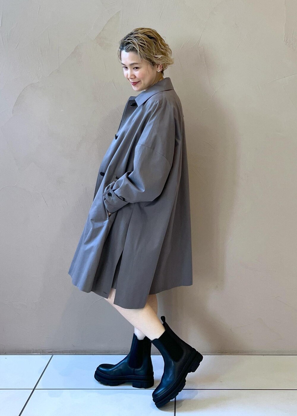 ブラック系のブーツ、ホワイト系のニット/セーター、グレー系のステンカラーコートを着用したレディースの冬コーディネートの4枚目の写真